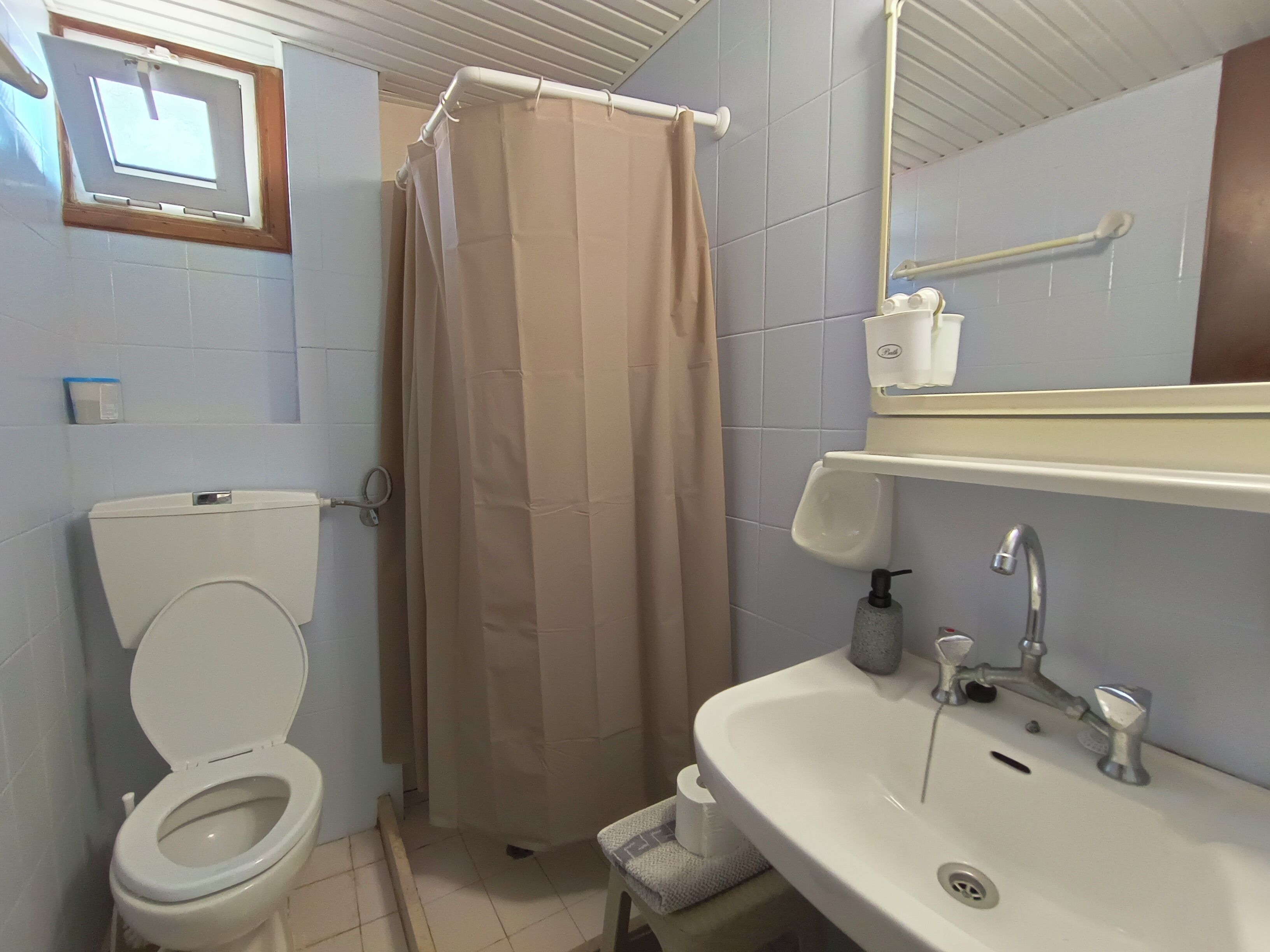 A bathroom with a toilet, shower curtain, sink, and a mirror.