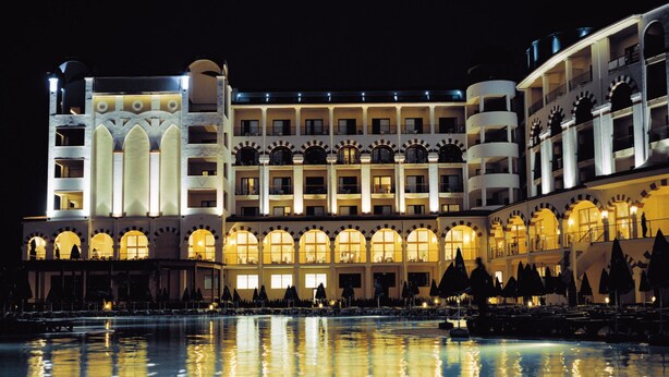 A large hotel with multiple balconies and a pool area.