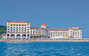 A large hotel with multiple balconies and a beach in the foreground. - Alua Helios Bay (Nessebar)
