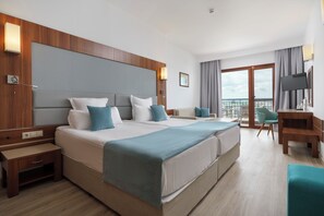 A hotel room with a large bed, bedside tables, a desk, and a balcony with a view.