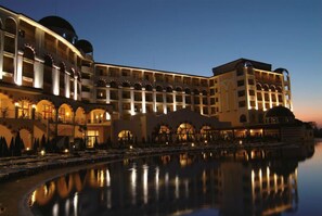 A hotel with multiple floors, a pool, and a waterfront view.