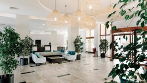 A spacious lobby with modern furniture, large windows, and hanging pendant lights.