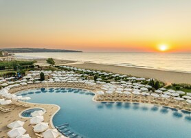 A resort with a pool, beach, and sunset view.