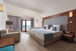 A modern hotel room with a large bed, a sofa, a TV, and a balcony with a view. - Alua Helios Bay (Nessebar)