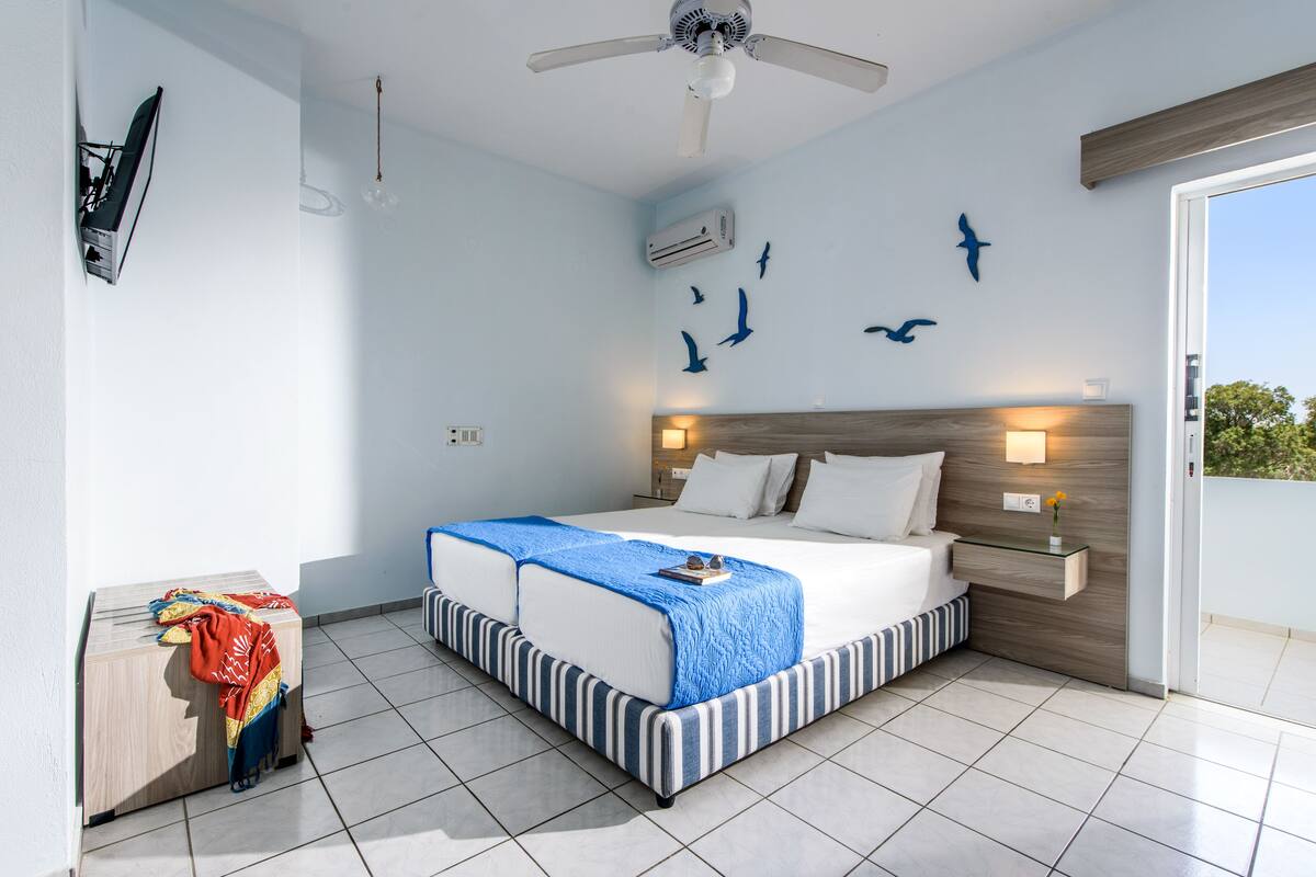 A bedroom with a bed, a bedside table, a ceiling fan, and wall decorations.