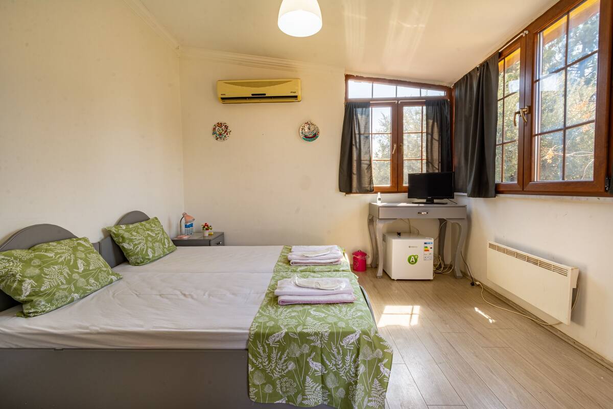A bedroom with a bed, a desk, and a window.