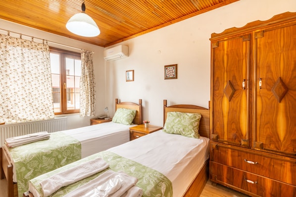 Habitación doble con dos camas, un armario de madera, una ventana con cortinas e iluminación en el techo.