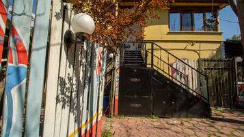 Un edificio con fachada amarilla, una verja negra y una escalera que conduce a la entrada.