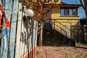 Un edificio con fachada amarilla, una verja negra y una escalera que conduce a la entrada.