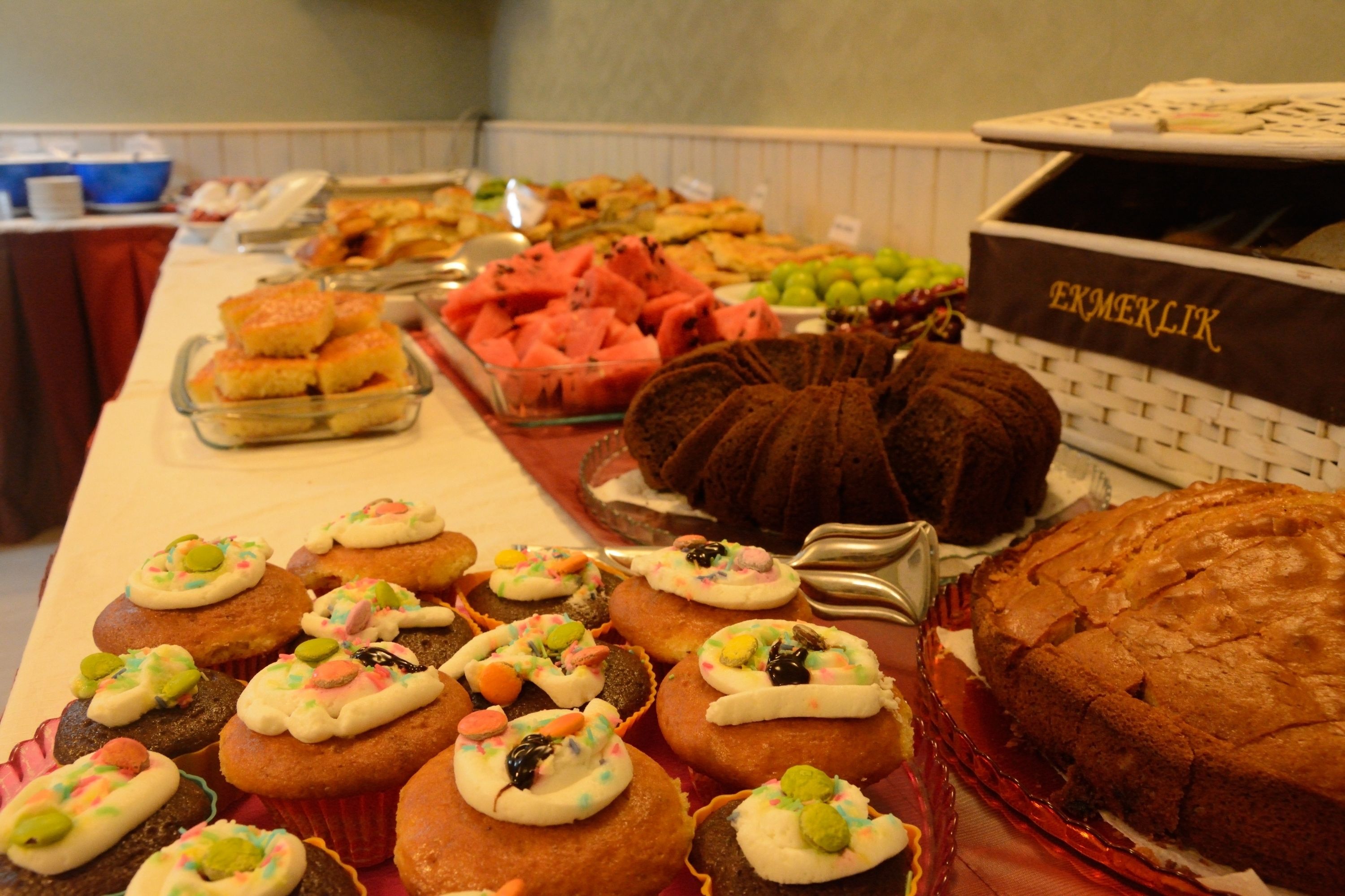 A buffet table with various food items including cakes, pastries, and fruits.
