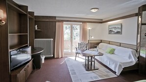 Hotellihuone, jossa on sänky, työpöytä, tuoli, patteri ja televisio.