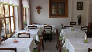 Comedor con varias mesas y sillas, cada una cubierta con un mantel blanco.