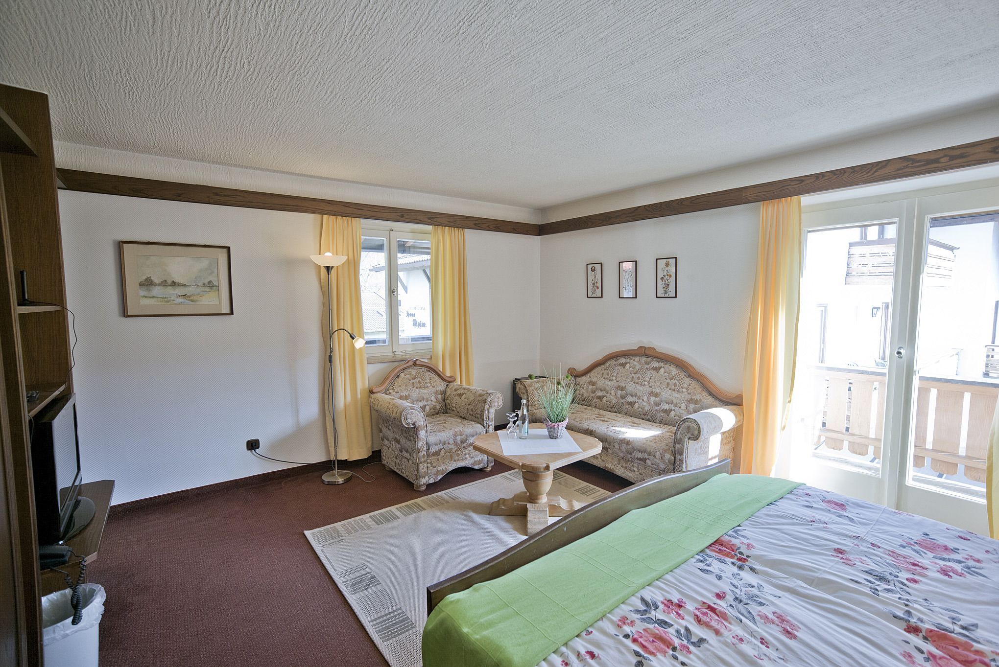 Un dormitorio con cama, dos sofás, una mesa y una ventana con cortinas.