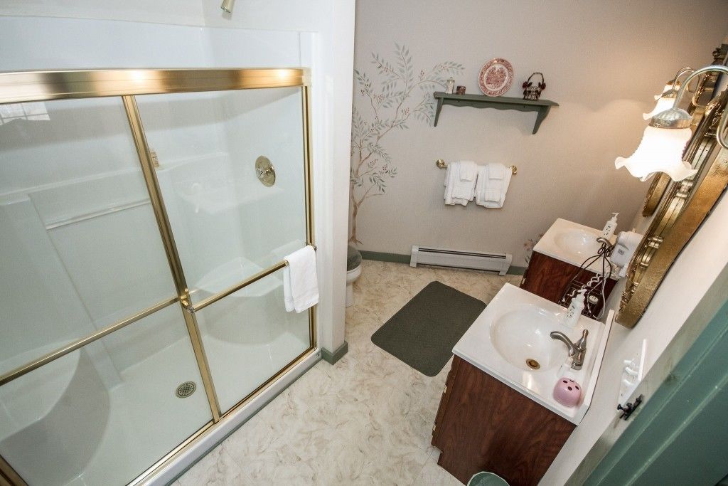 Un baño con cabina de ducha de vidrio, un lavabo con espejo y un perchero para toallas.
