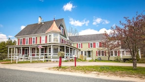 A historic building with a prominent corner turret and a wrap-around porch. - Rosewood Country Inn (Bradford)
