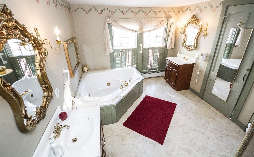 Un baño con una bañera grande, dos lavamanos y espejos ornamentados.