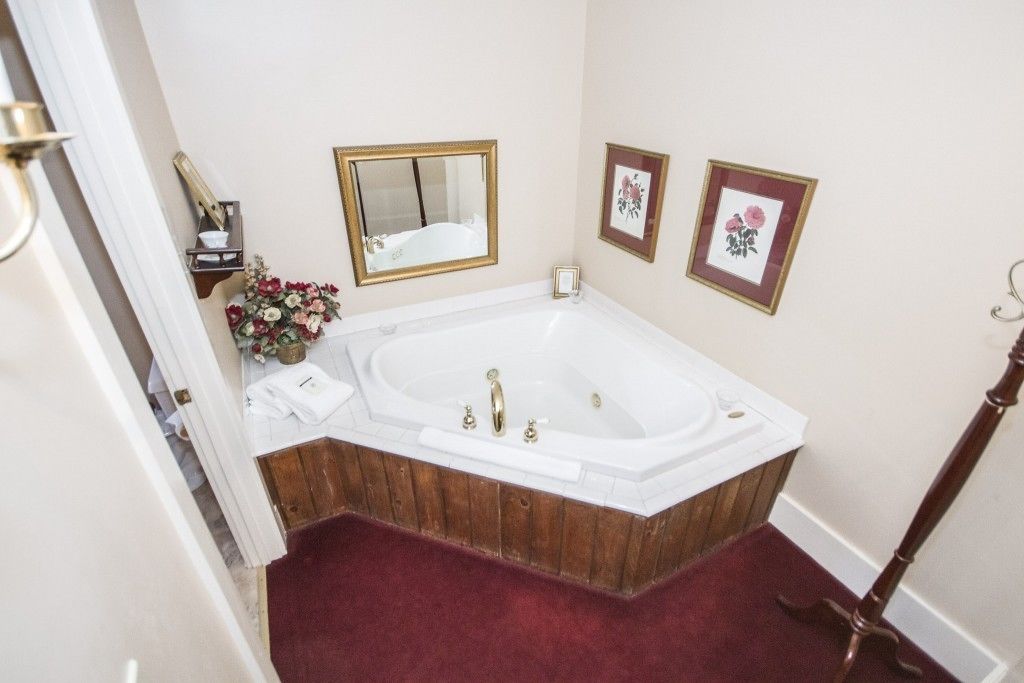A bathroom with a freestanding bathtub, a wooden vanity, a mirror, and two framed floral pictures on the wall.