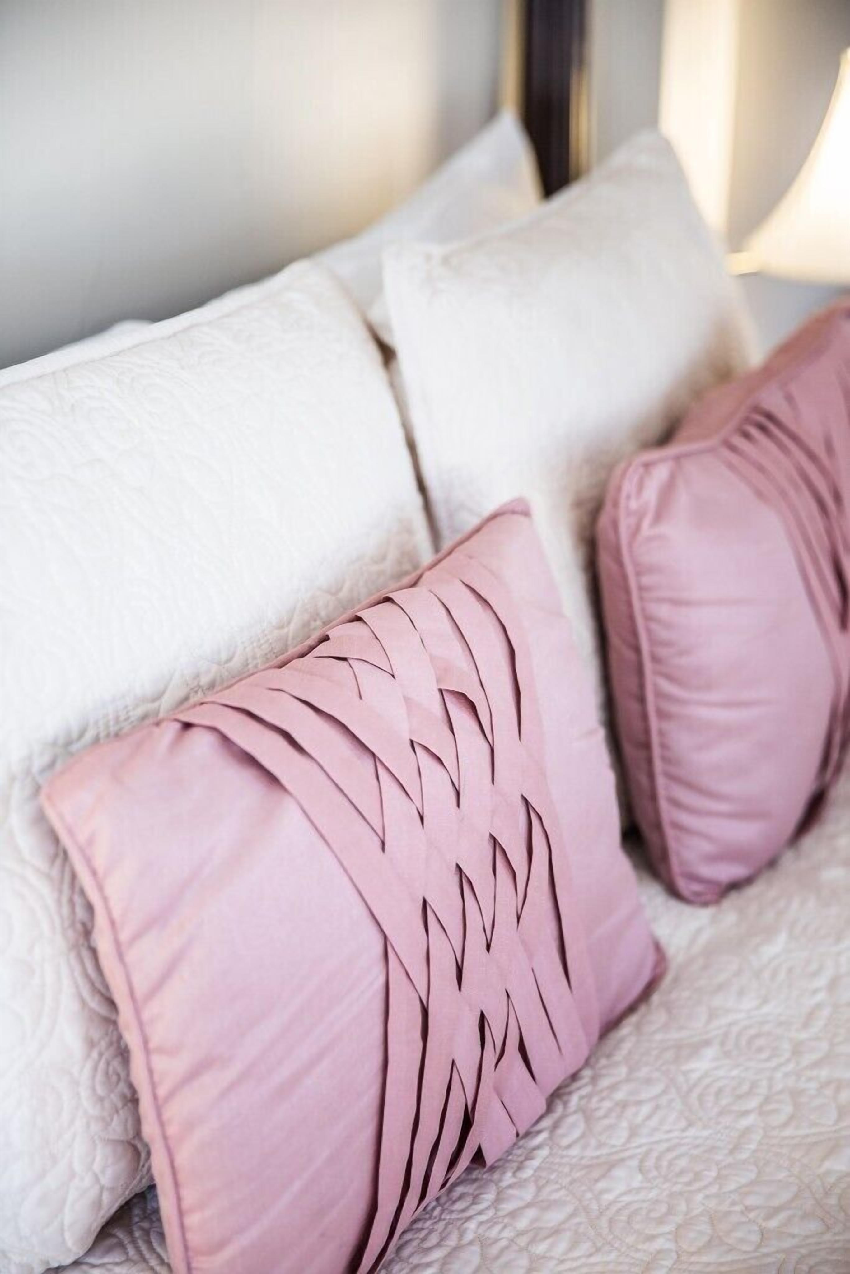 Un sofá blanco con tela texturizada y dos almohadas rosas con diseño geométrico.
