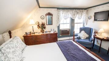 Quarto com cama, cômoda, cadeira e televisão na parede.