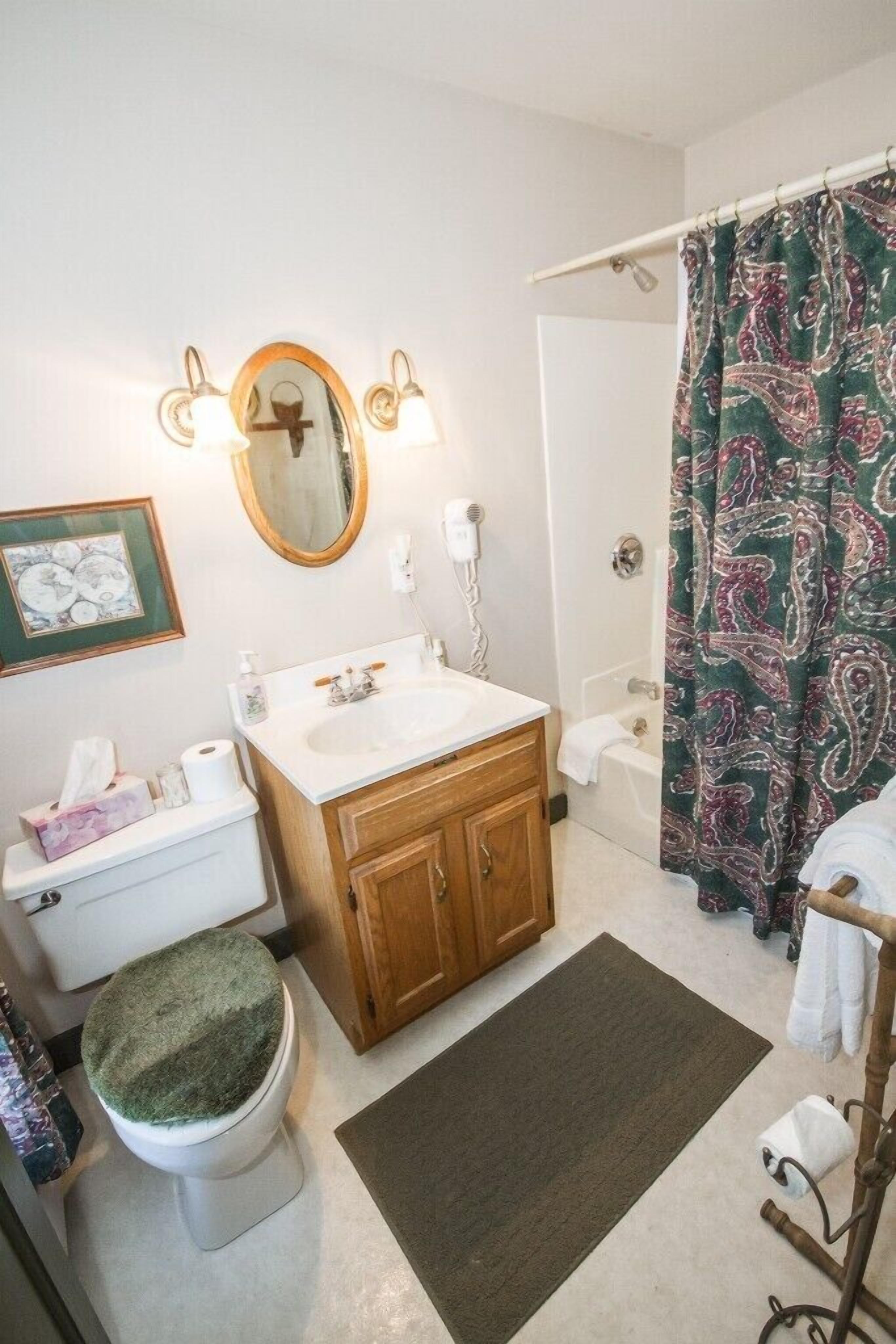 A bathroom with a wooden vanity, a white sink, a mirror, and a shower curtain.