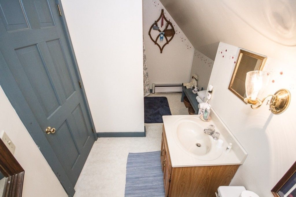 A bathroom with a white sink, wooden vanity, and a blue door.