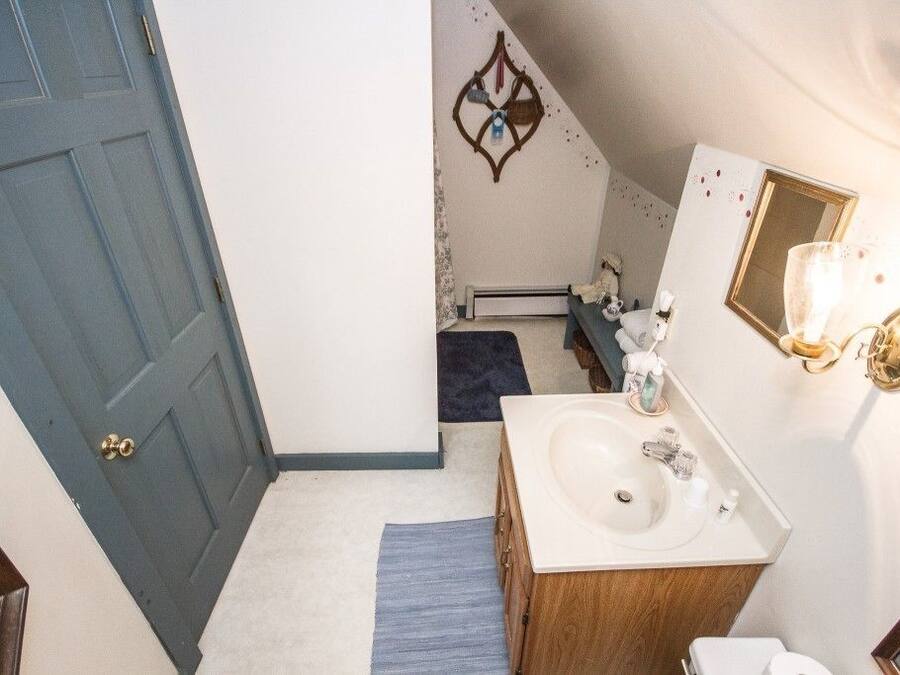 A bathroom with a white sink, wooden vanity, and a blue door.