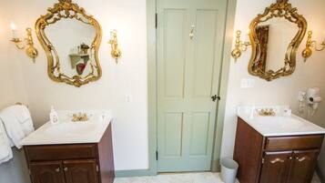 Un baño con dos lavamanos, una puerta verde y espejos adosados a la pared con detalles dorados.