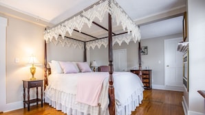A four-poster canopy bed with a lace canopy, a bedside table with a lamp, and a wooden floor. - Rosewood Country Inn (Bradford)