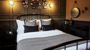 Un dormitorio ordenado con cama, mesitas de noche, un espejo y lámparas de pared.