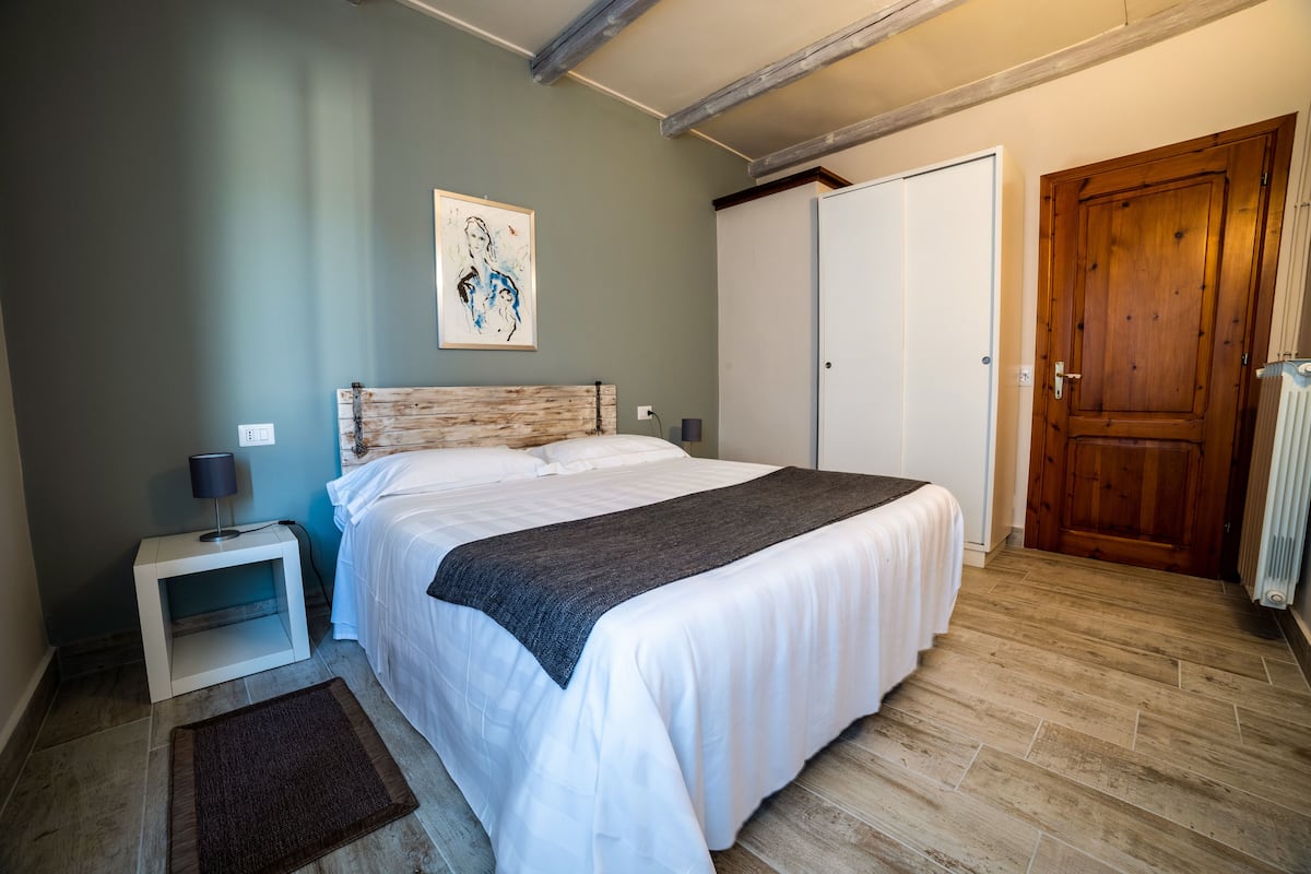 A bedroom with a bed, a nightstand, a wooden door, and a radiator.