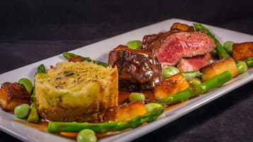 A plated dish with steak, potatoes, asparagus, and peas.
