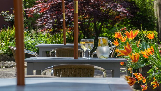 An outdoor seating area with a table, chairs, and a pitcher of water. - Old Kings Arms Hotel (Pembroke)
