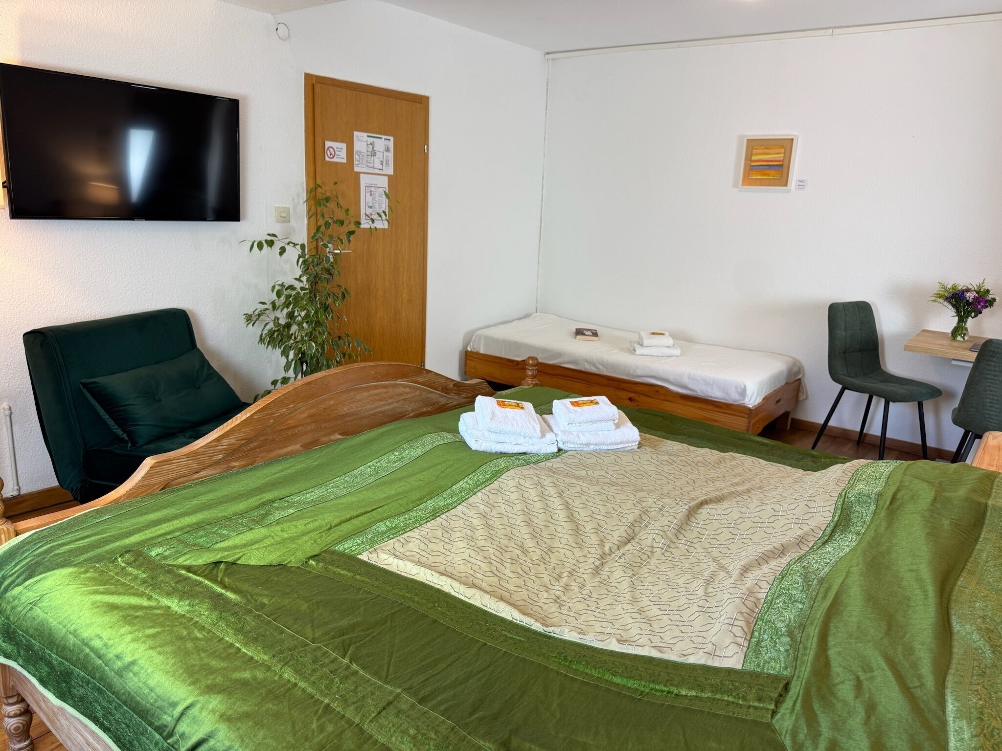 Habitación de hotel con una cama grande, un escritorio, una silla, un televisor y una puerta con avisos.