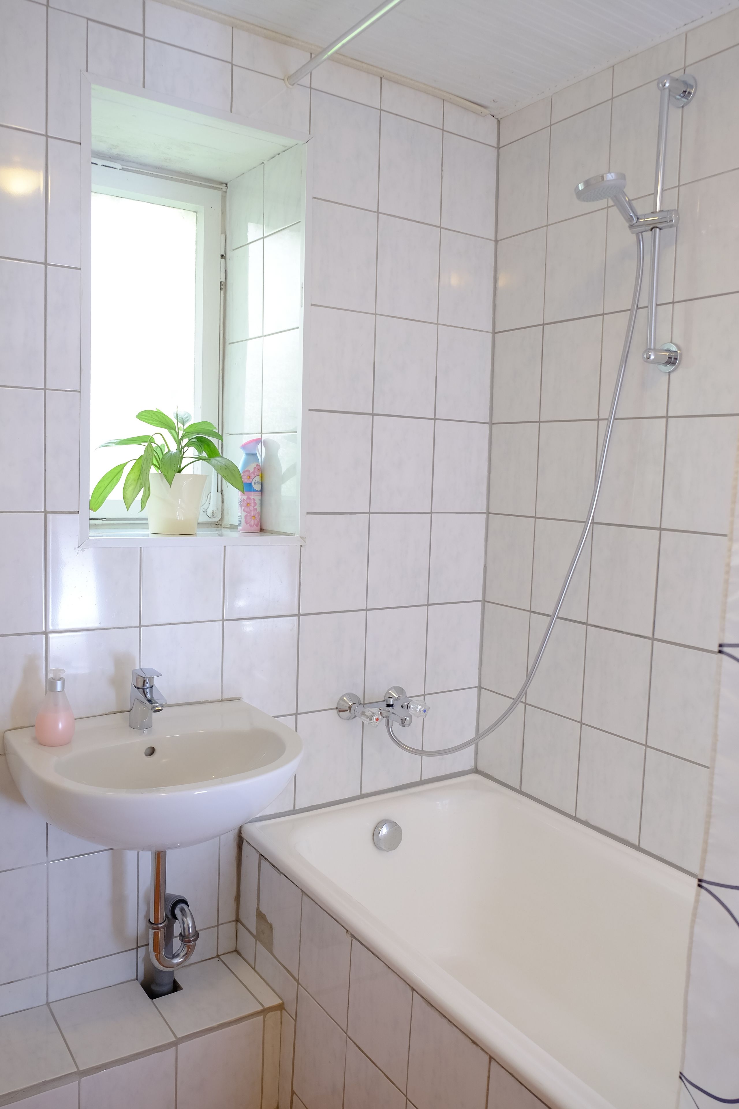 A bathroom with a white sink, mirror, and shower.
