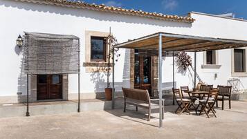 Une terrasse avec une table et des chaises en bois, un banc et une pergola.