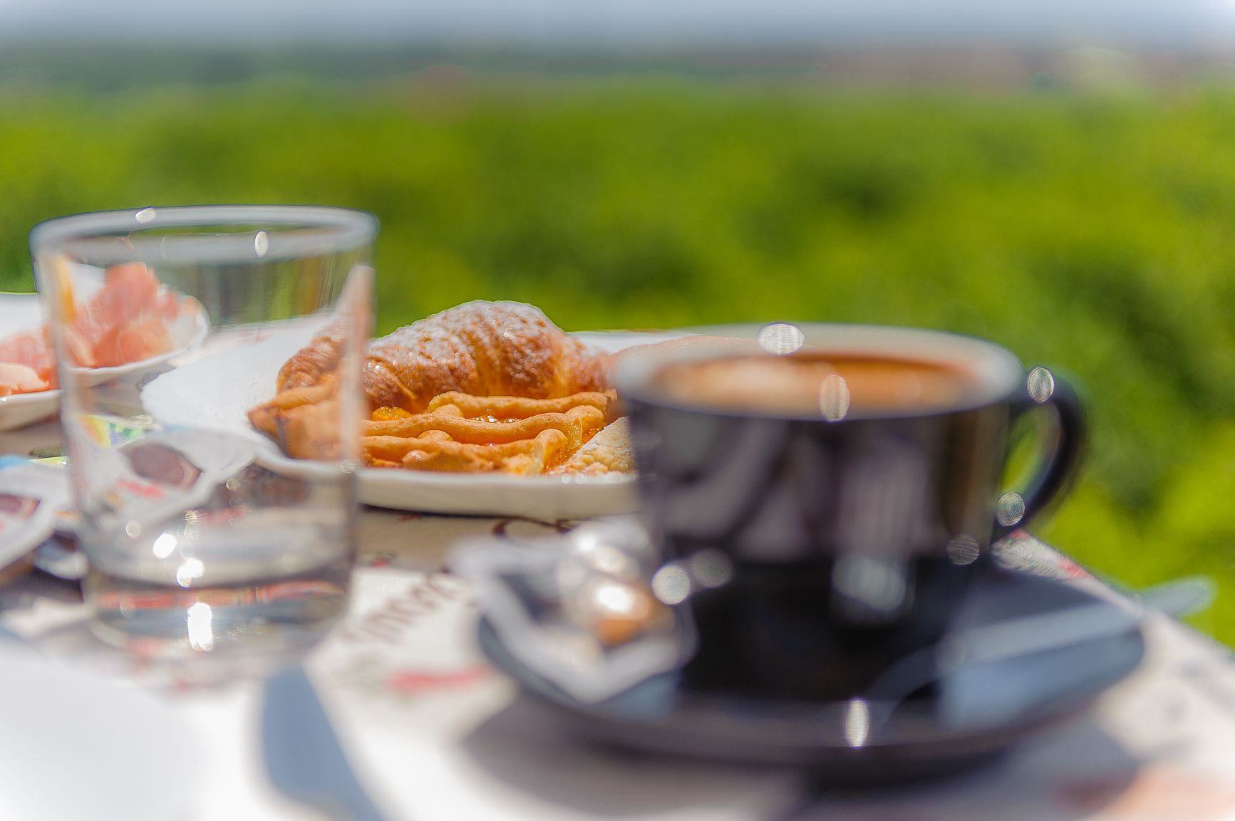 A table with a cup of coffee, a glass of water, and pastries.