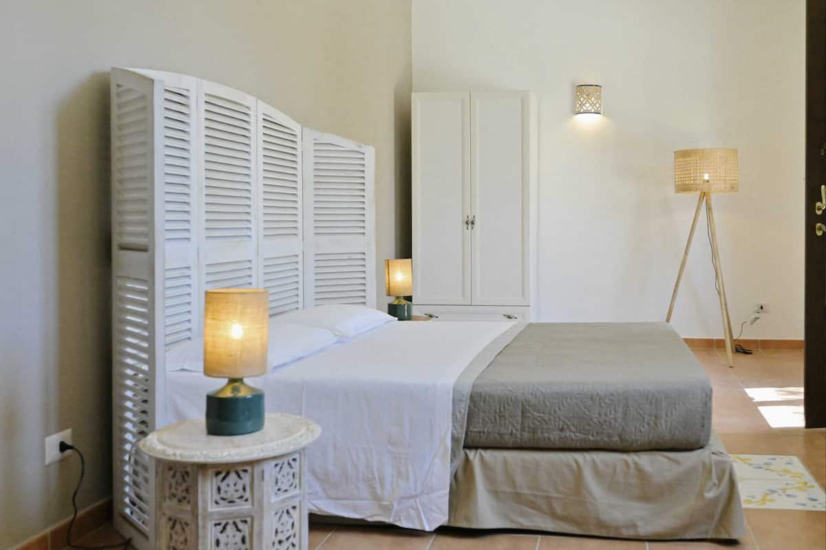 Ein Schlafzimmer mit einem Bett, Nachttischlampen, einem Kleiderschrank und einer Stehlampe.