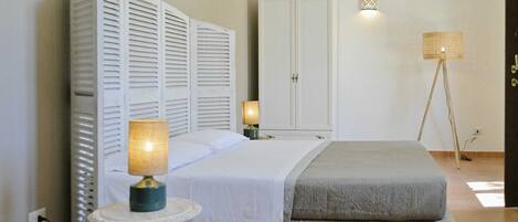 Een slaapkamer met een bed, nachtlampen, een kledingkast en een staande lamp.