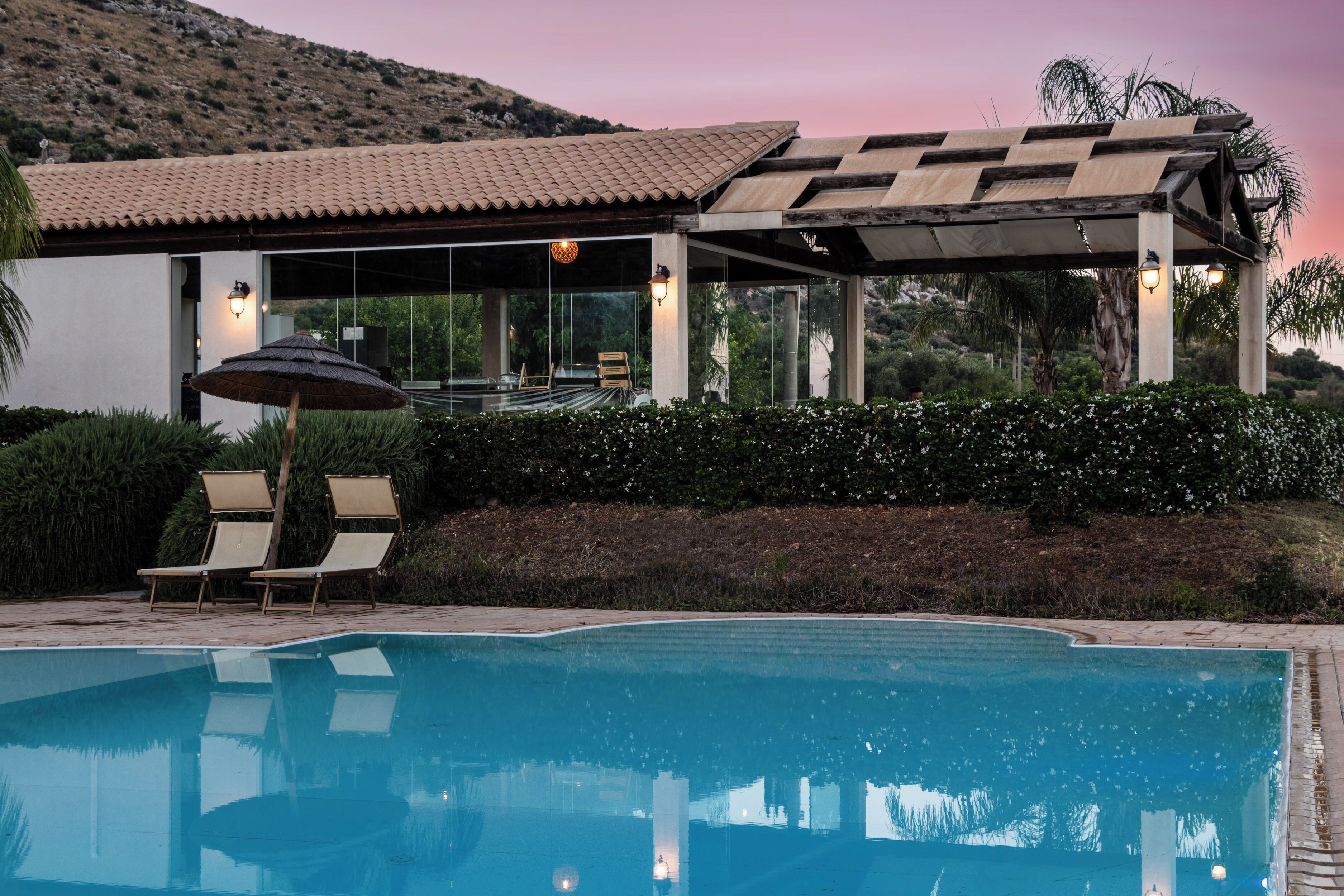 Ein moderner Poolbereich mit klarem Pool, Liegestühlen und einer Pergola.
