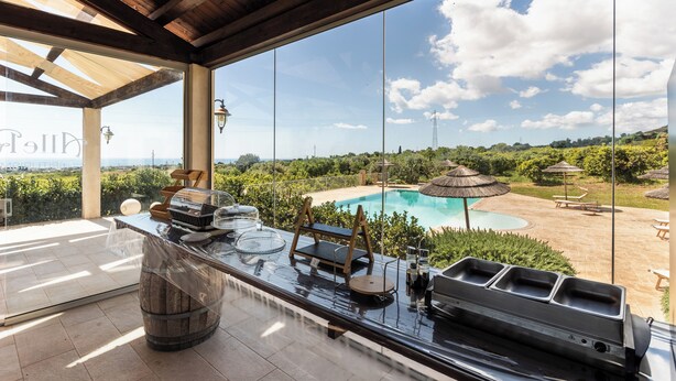 A bar area with a pool view, wooden beams, and outdoor seating.