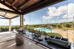 Zona de bar con vista a la piscina, vigas de madera y asientos al aire libre.
