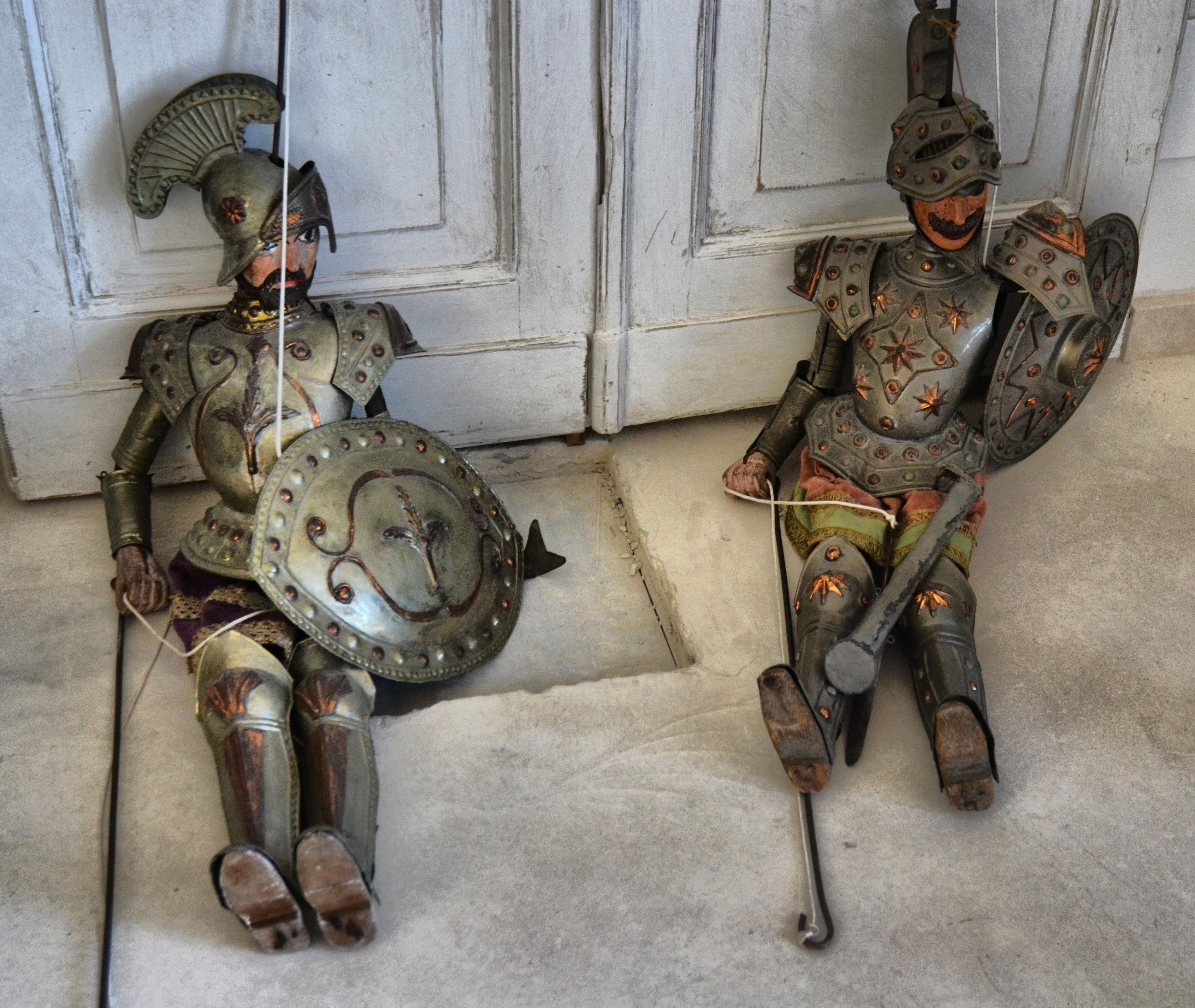 Dos soldados romanos antiguos, con armadura, sentados sobre un suelo de piedra.
