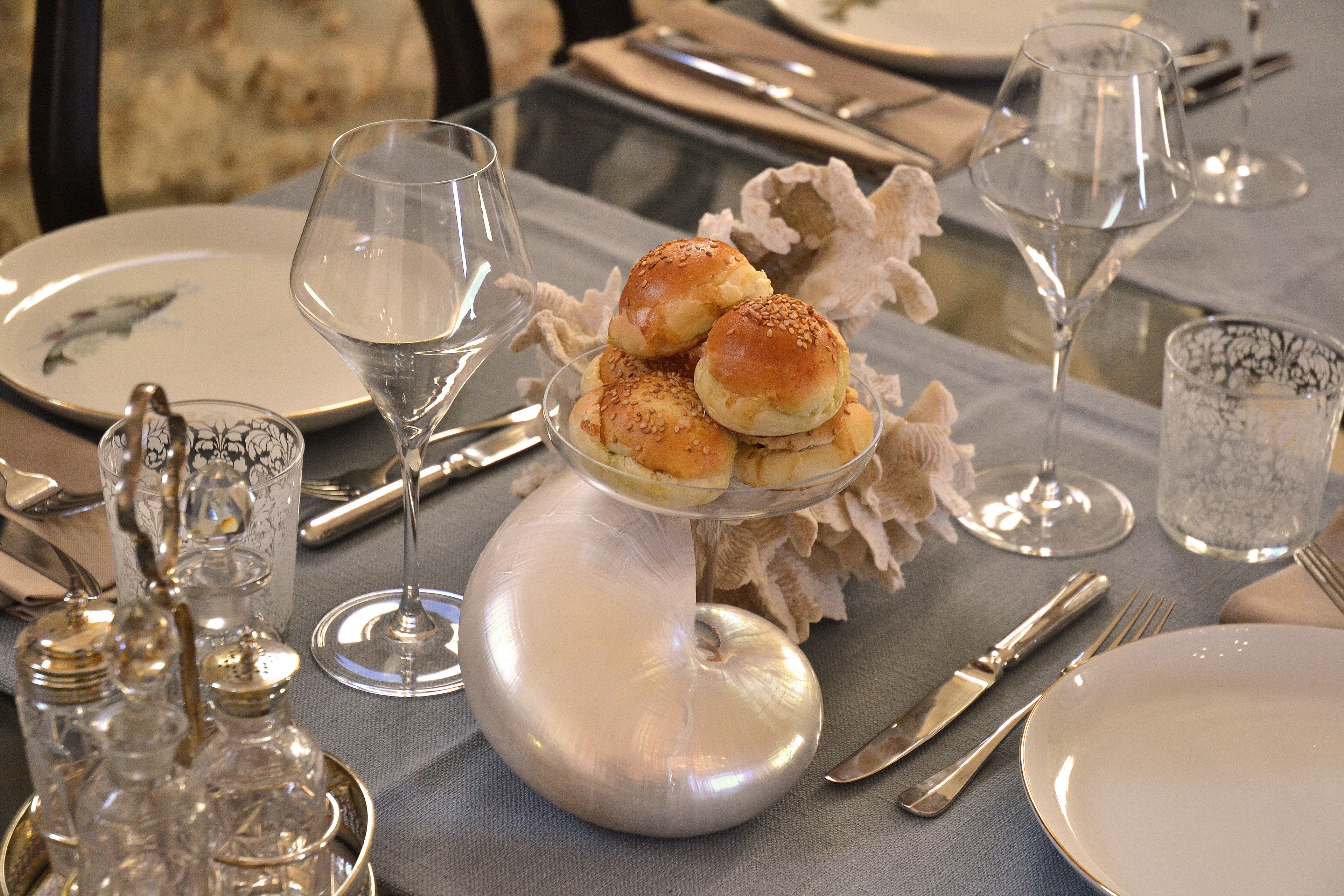 A table set with dinnerware, including plates, glasses, and cutlery.