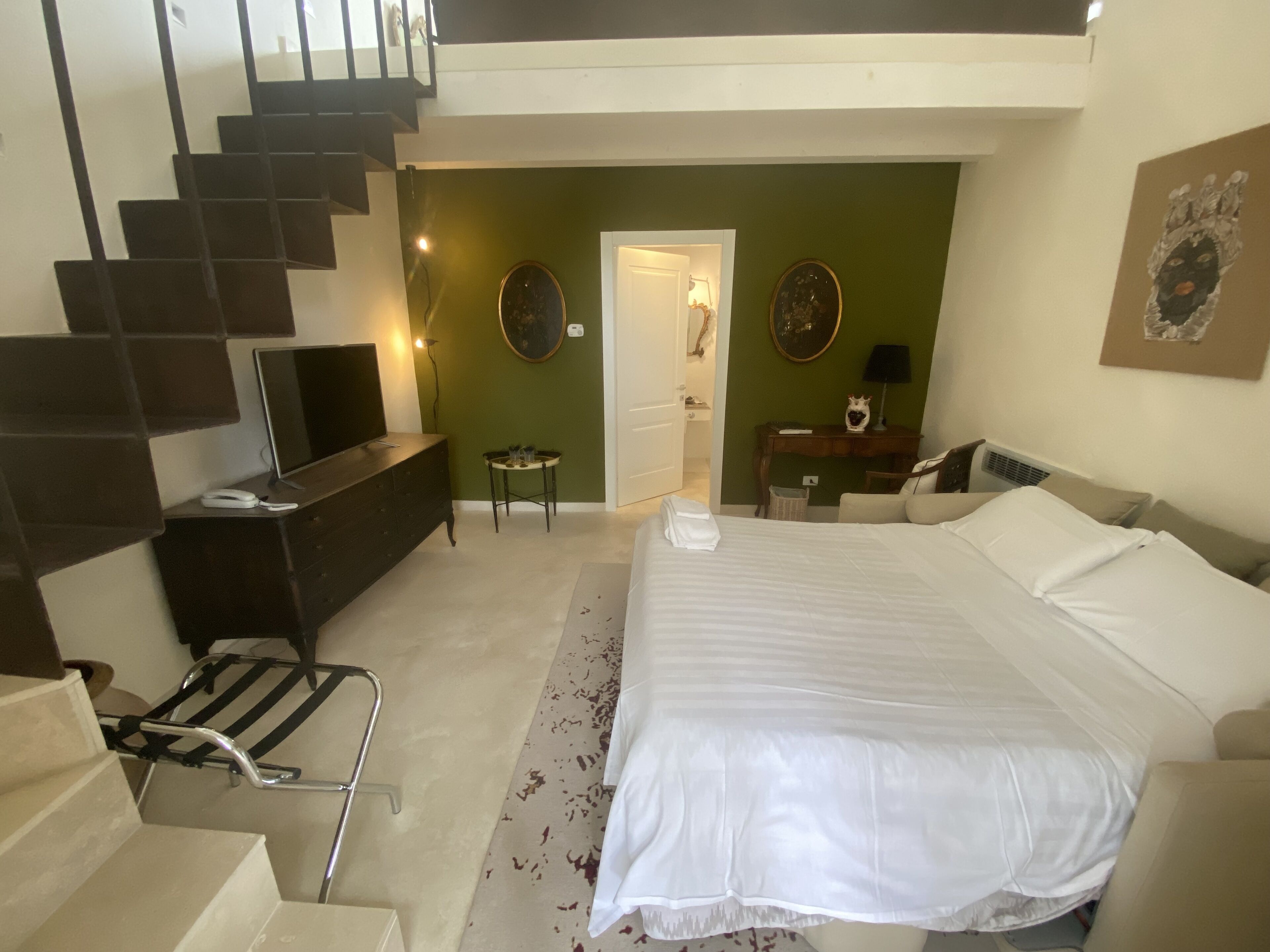 Quarto com cama, penteadeira e escada que dá para um andar superior.
