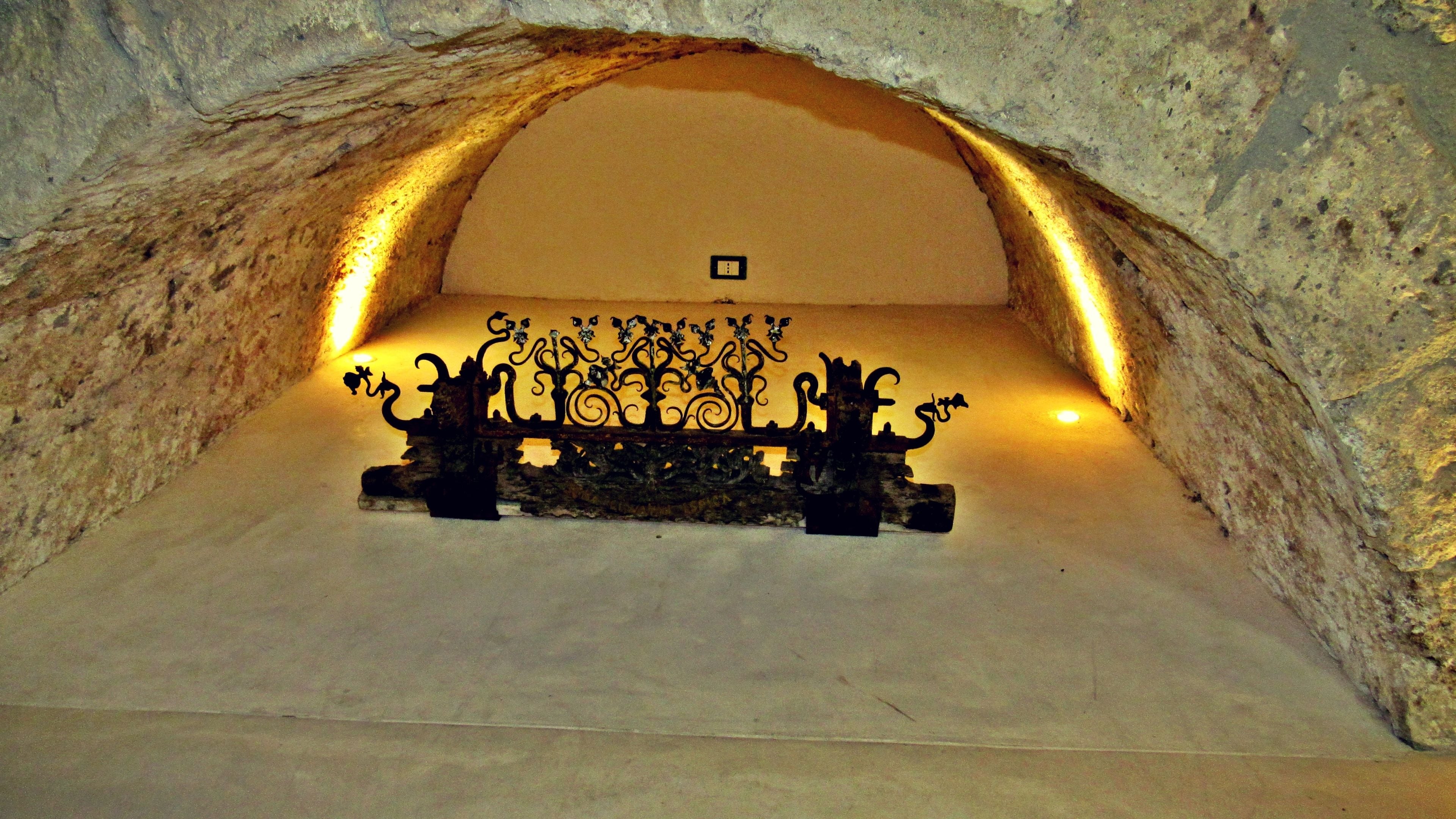 An underground room with a decorative metal gate and a small square object on the wall.