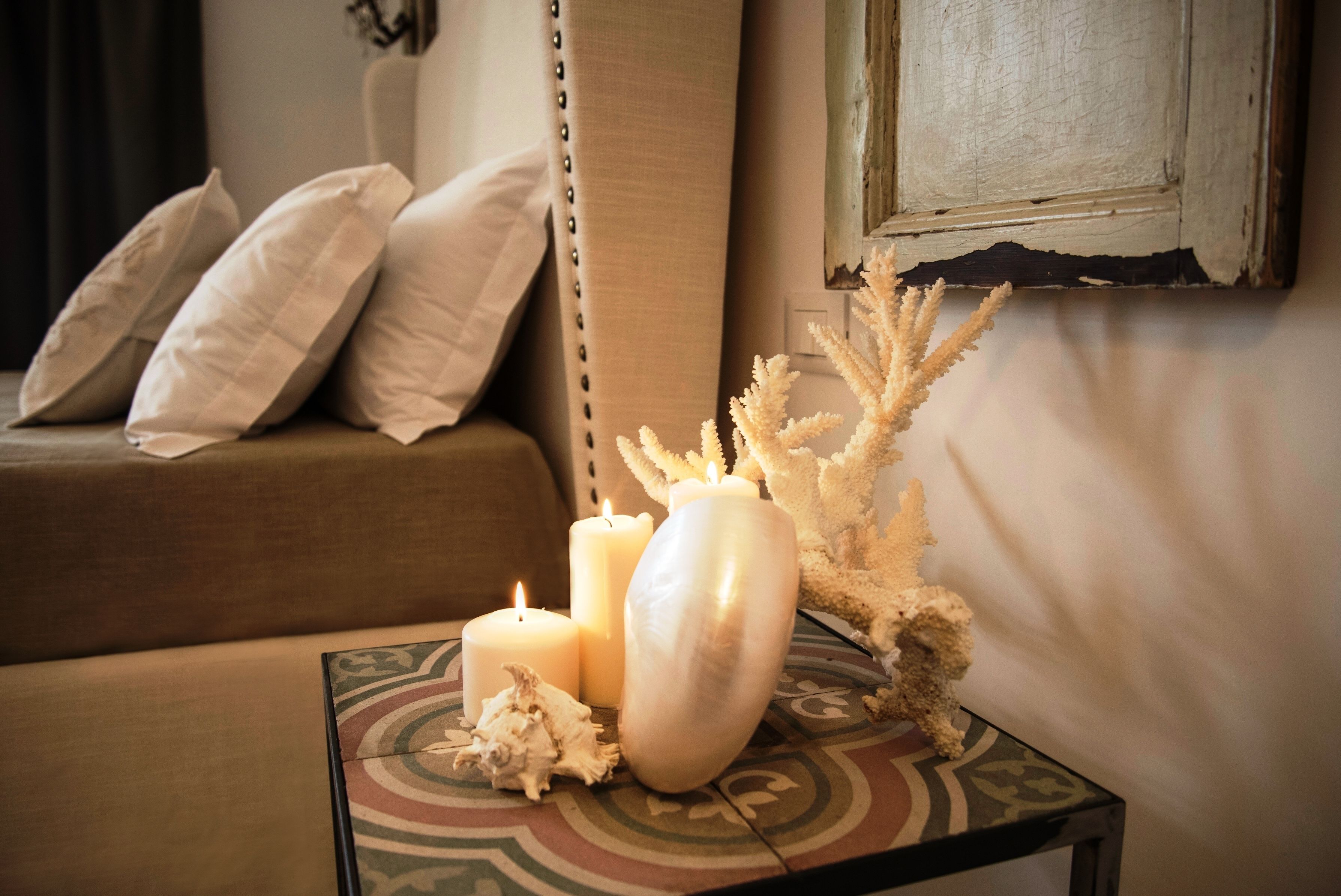 Um quarto acolhedor com sofá, uma mesinha com velas e objetos decorativos.