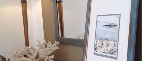 Une photographie encadrée représentant un paysage avec un bateau, une lampe et un objet décoratif en forme de corail, le tout posé sur une table à motifs.