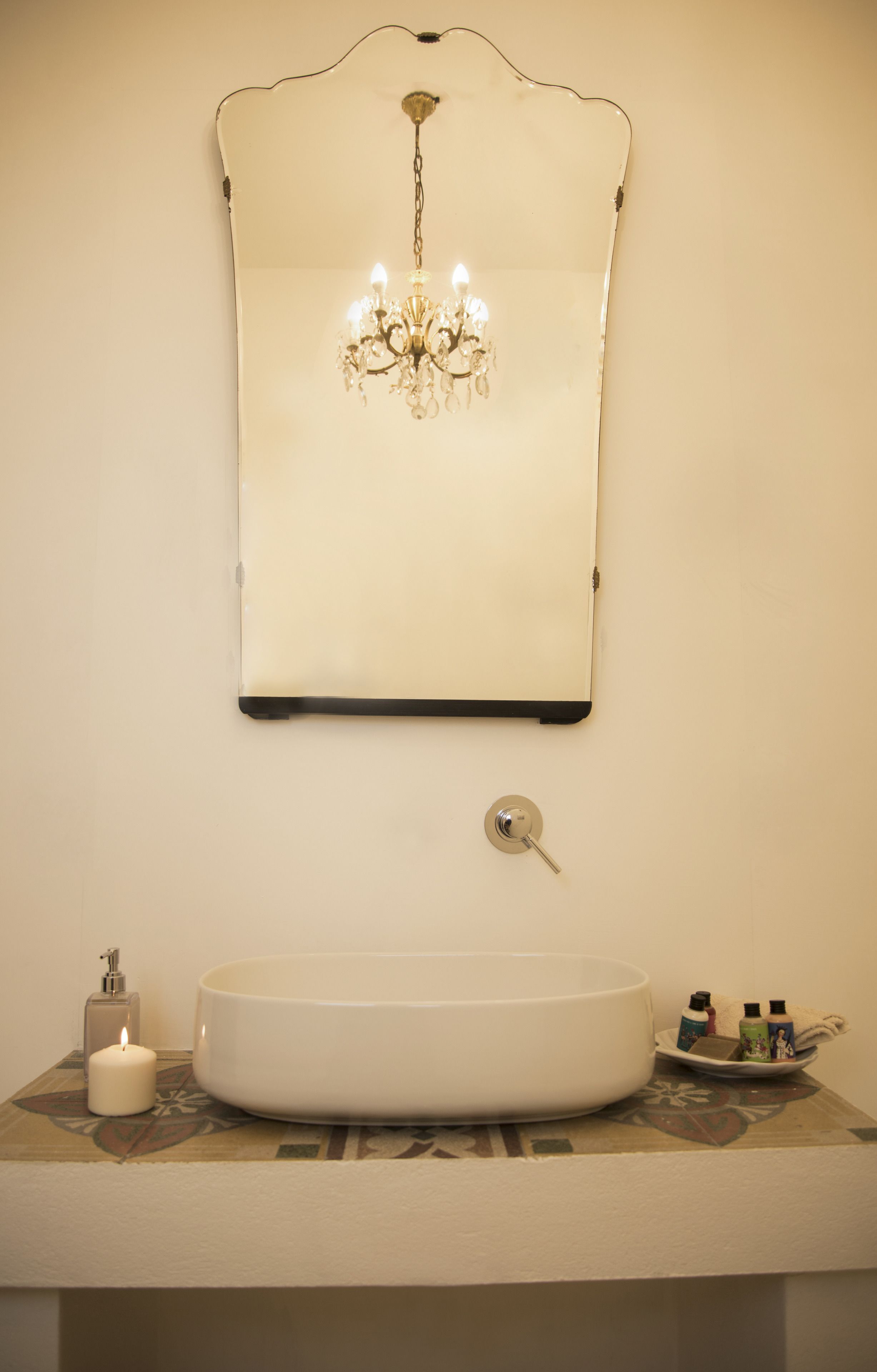 A bathroom with a white sink, a chandelier, a key, and toiletries.