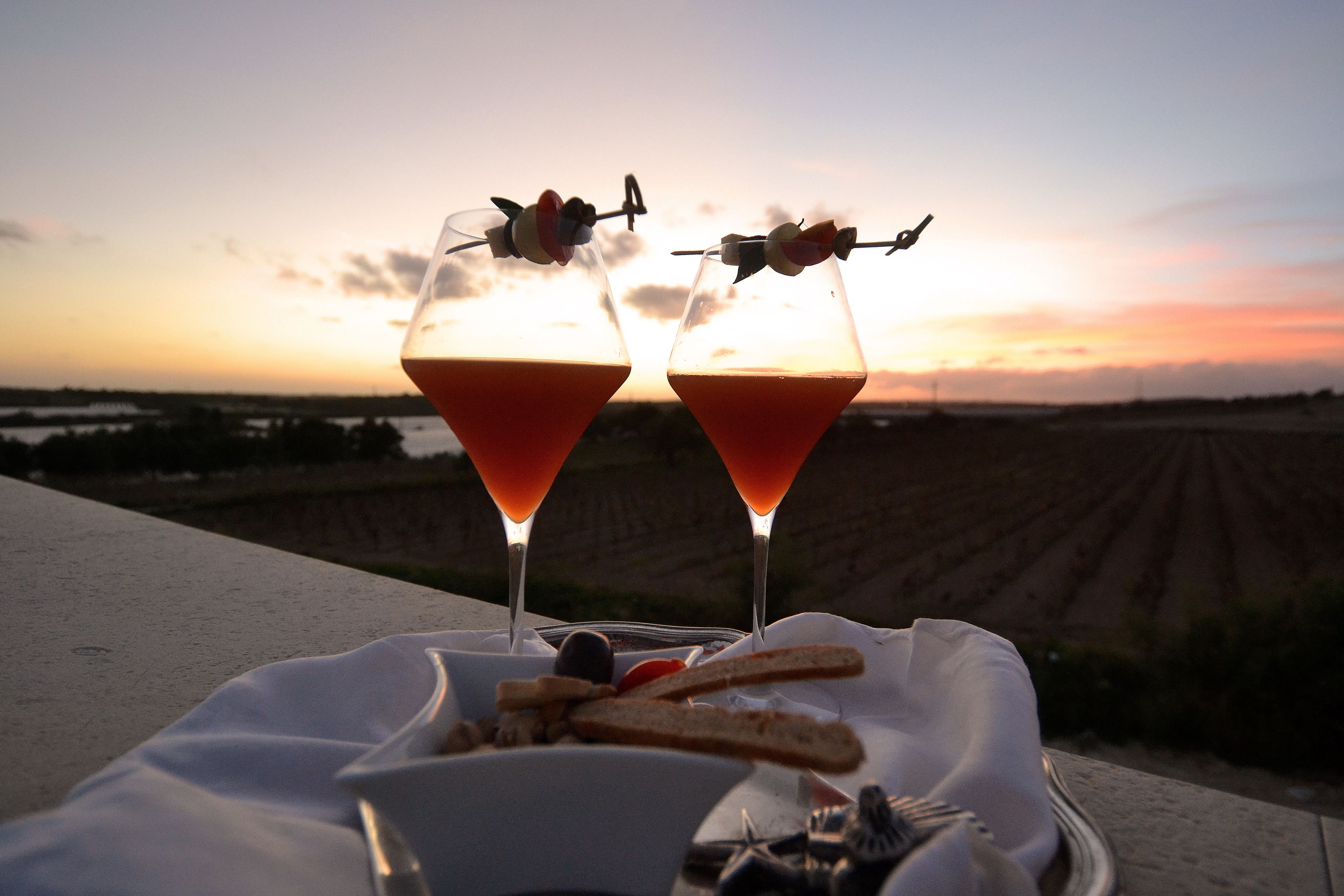 Two martini glasses with a sunset in the background.