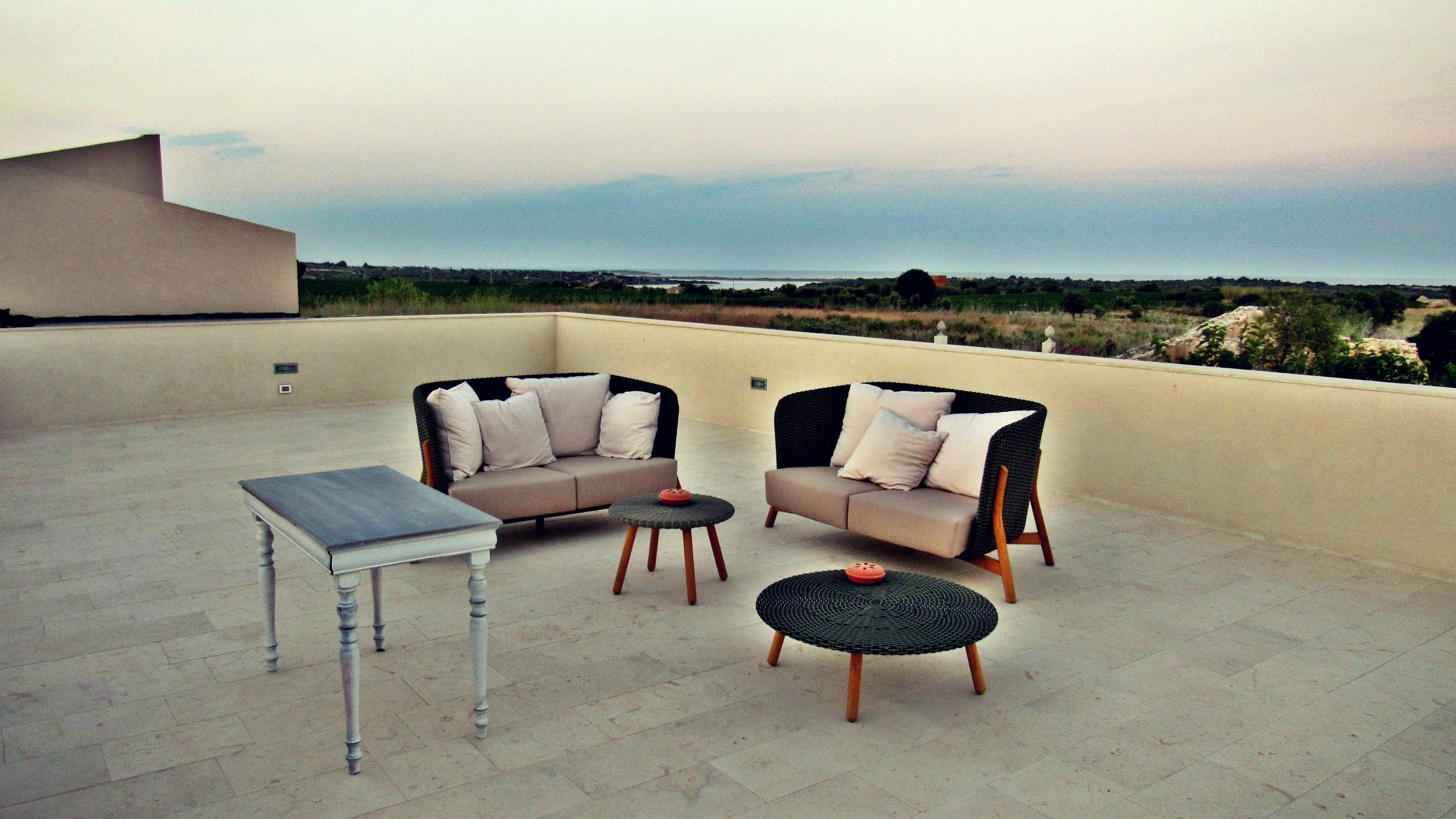 Eine Dachterrasse mit zwei Sofas, einem kleinen Tisch und einem runden Tisch.